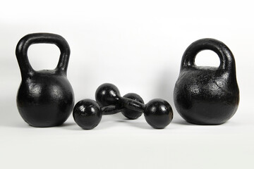 Naklejka na ściany i meble Ancient iron kettlebells and dumbbells on a light background, to strengthen the upper body. Kettlebells and dumbbells were already rusty from time but they were restored, painted