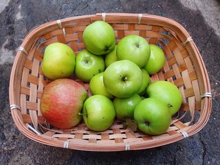 Green apples from an Apollo Rocket tree freshly picked in a wicker basket during the Autumn fall, stock photo image