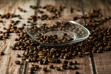 Homemade composition of scattered coffee and a glass saucer