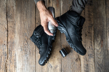 Boots care, shoes care. Man applying a special waterproof spray to trekking shoes. Top view.