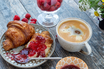 Croissant with a berry jam and a cup of fresh coffee