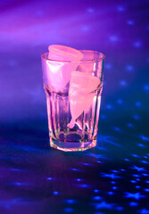 two pink menstrual cups in a glass cup on a purple background background with stars photo