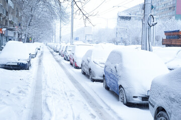 Parked cars covered in snow and urban street