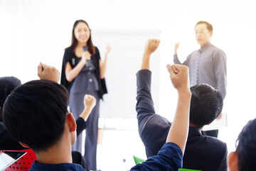 Senior Asian Lecturers is lecturing about business and stock market topics and business people are having a seminar and raising hands for powerful in the economics class meeting room. Focus on hands