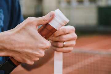 Process of replacement grip on tennis racket. Overgrip. Close-up of hands.