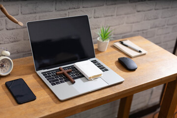 Study Bible online concept. Wooden cross and laptop on wooden table.