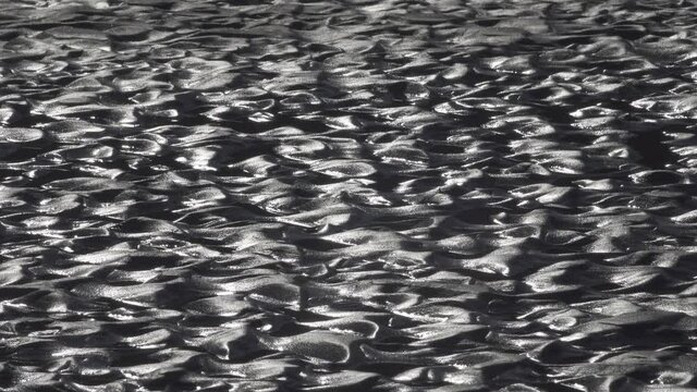 Patterned holes on the sandy surface of the beach on the shallows (river shoal) at sunset. The work of water current, human feet and wind. Design pattern effect ("the surface of the moon")