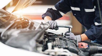 Mechanic works on the engine of the car in the garage. Repair service. Concept of car inspection...