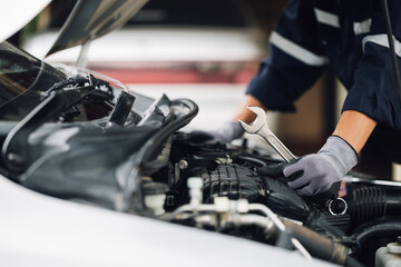 Mechanic works on the engine of the car in the garage. Repair service. Concept of car inspection service and car repair service.