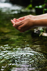 Beautiful male hands taking fresh water from the crystal-clear river