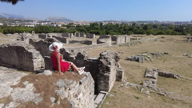 Elegant lady with hat in Salona ruins. Ancient Roman city and capital of the Roman province of Dalmatia in Croatia. Old Roman archeological site and the birthplace of Emperor Diocletian.