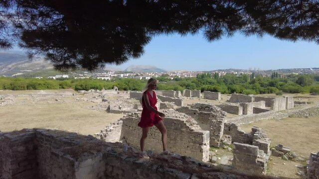 Tourist woman walking in the Salona ruins Ancient Roman city of Dalmatia in Croatia. Historic Roman town ruins and City basilica remnants in the Episcopal Center.