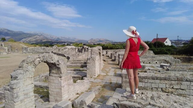Tourist woman in the Salona ruins of the Ancient Roman Amphitheatre of Dalmatia in Croatia. Historic Roman coliseum in Flavian architectural style.