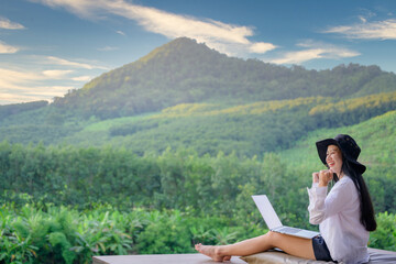 Asian female tourists visiting Thailand Travel that she likes to travel in style. Forests and natural waterfalls beautiful mountains Work on a happy holiday with freelance work on a laptop.