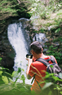 Man taking pictures of a waterfall in the forest