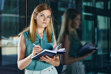 Female manager writes notes near business center in notebook.