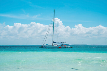 Cancun, Mexico. May 30, 2021. Yacht or sailboat sailing on beautiful turquoise sea water surface against cloudy sky