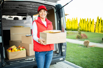 Portrait of hardworking female courier holding package before delivery. - obrazy, fototapety, plakaty