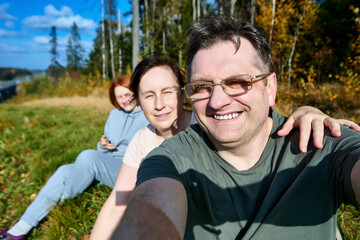 European family is making selfie during sitting in forest.