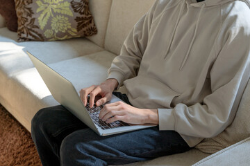 Flat view of young man working on the couch with his laptop at home shows the concept of working on the internet with digital networks from anywhere