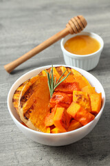 Baked pumpkin, honey and dipper on gray textured background