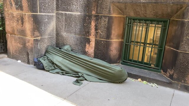 church tilt down to homeless asleep under blanket - person sleeping on sidewalk - homelessness in the street - New York City NYC