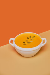 Pumpkin soup decorated basil on orange background