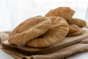 Stack of pita bread on a wooden board, hot from the oven. Homemade, freshly baked gluten-free...