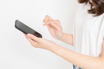 スマホを操作するTシャツを着た若い女性