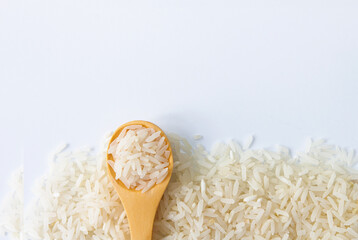 Uncooked dry rice in wooden spoon on white background.