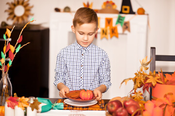 Boy served festive table and decorating living room for celebrating Thanksgiving day.