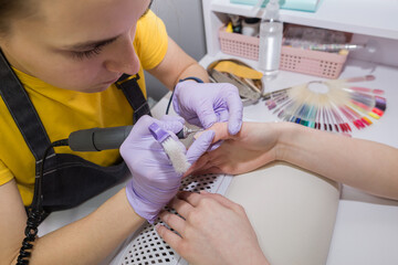 Modern electrical equipment for a beauty salon. A master in gloves makes a hardware manicure for a client in a studio with manicure equipment