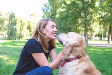 young blonde woman with her dog retriever in the park