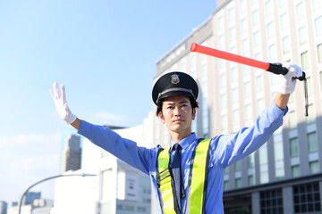 誘導棒を持つ交通誘導をするガードマンの男性