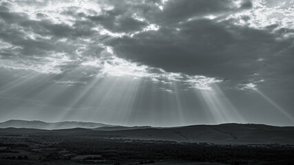 Monochrome photo of bright pillars of sunlight pass through gloomy clouds. Holy Light comes from...