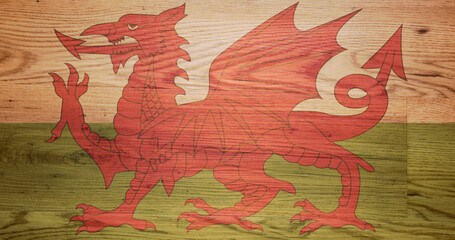 Symbolic Welsh Dragon flag transluscent laid over a wooden background