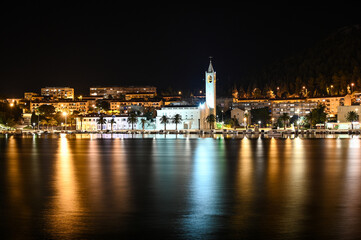 Fototapeta na wymiar City of Ploce and Adriatic sea in Croatia by night. Panoramic view of buildings in town reflected in the water. 