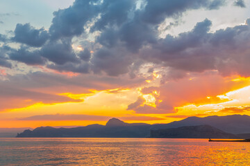 sunset over the mountains by the sea coast