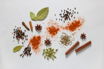 Aassorted colorful spices on grey background, flat lay, top view. Cloves, cardamon, coriander, anise, pepper, paprika, cumin, cinnamon.