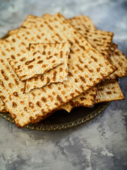 A stack of traditional Jewish matzah bread on a plate. Light background. Low angle view. Close-up. Jewish Passover, a traditional holiday treat. There are no people in the photo. Advertising, postcard