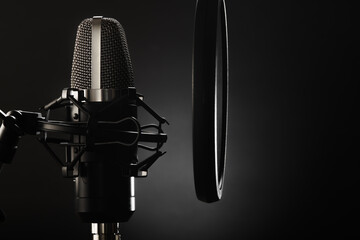 Studio microphone and pop filter on a dark gray background. Minimalism. There are no people in the...