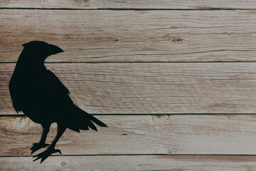 Raven silhouette on wooden background. Halloween. Copy space.