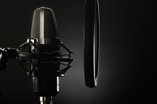 Studio microphone and pop filter on a dark gray background. Minimalism. There are no people in the photo. Close-up. Recording studio, radio, television, vocals, conversational genre.