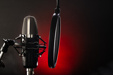 Professional microphone and pop filter on a black-red background. Broadcasting, television,...