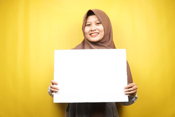 Pretty young muslim woman cheerful holding blank empty banner, placard, white board, blank sign board, white advertisement board, presenting something in copy space, promotion