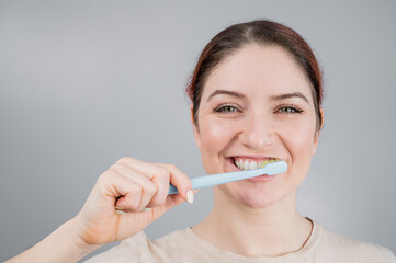Close-up portrait of caucasian woman brushing her teeth. The girl performs the morning oral hygiene...