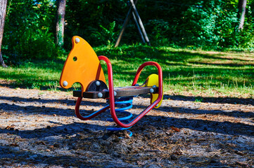 Children's playground with a swing toy in the foreground in a forest in Berlin, Germany.