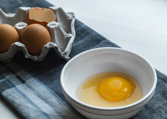 A plate with a broken egg near a chicken box on a gray napkin on the table.