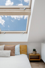 Skylight window over comfort bed in white bedroom interior