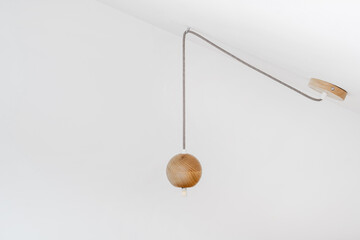 Wooden ceiling lamp hanging against white wall